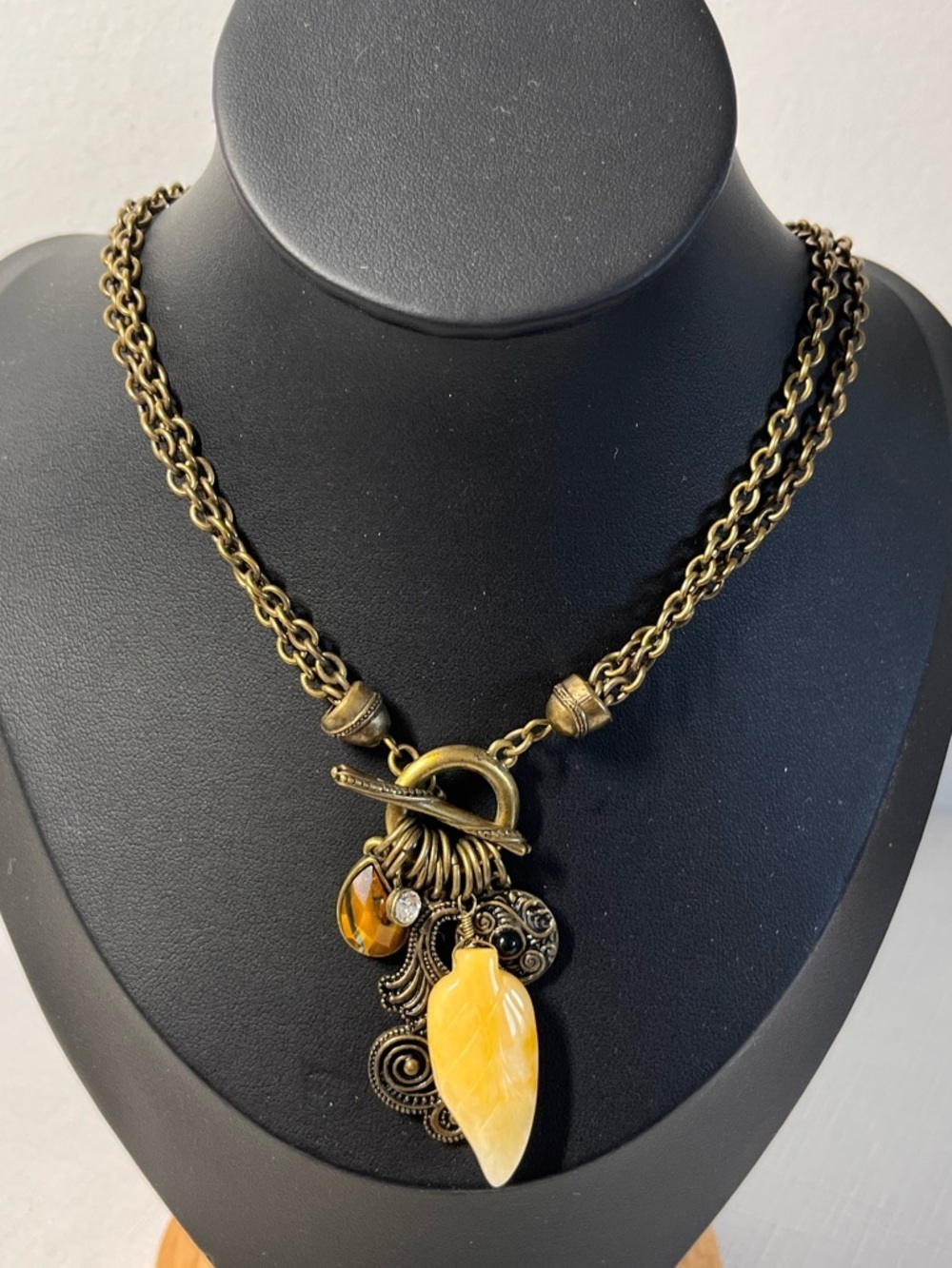 Bronze tone necklace w a large yellow pendant and smaller charms; toggle clasp